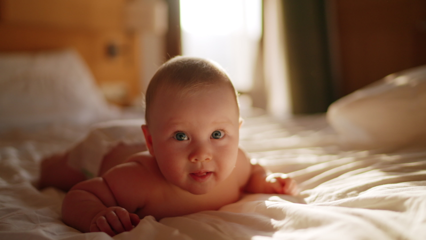 Beautiful Smiling Baby, gorgeous little baby lie on bed and smile at camera with nice soft focus background. Little girl or boy is humming, real original audio track, lovely asian baby playing at home | Shutterstock HD Video #1089248305