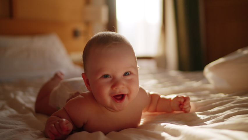 Beautiful Smiling Baby, gorgeous little baby lie on bed and smile at camera with nice soft focus background. Little girl or boy is humming, real original audio track, lovely asian baby playing at home Royalty-Free Stock Footage #1089248305
