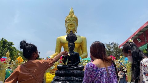 Pattaya, Thailand - April 14, 2022: People bath a Buddha image at the Big Buddha temple during the Songkran holiday. Songkran's water splashing is forbidden this year due to COVID-19 pandemic.