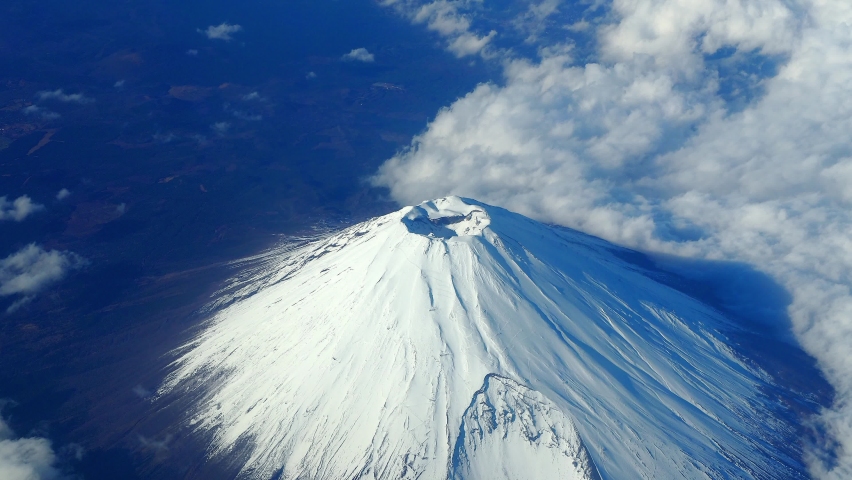 Top of Mt. Fuji.  Bird eyes view of big and high mountain Fuji of Japan. Mount Fuji Yama from sky above. Aerial view. With white snow on top and clouds around. Represent winter season of Japan. | Shutterstock HD Video #1089251279