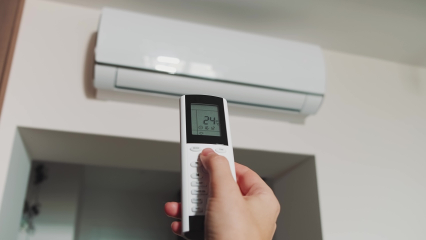Silhouette part of person body. Human hand uses remote control, presses buttons, sets selects temperature of air cooling in home with of modern technologies, internal air conditioner unit. White room Royalty-Free Stock Footage #1089252217
