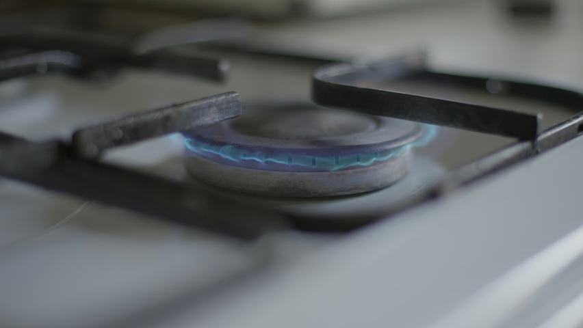 Close-up gas burning on stove burner with black stainless steel pot putting on. Unrecognizable person cooking dinner lunch indoors at home in kitchen Royalty-Free Stock Footage #1089255021