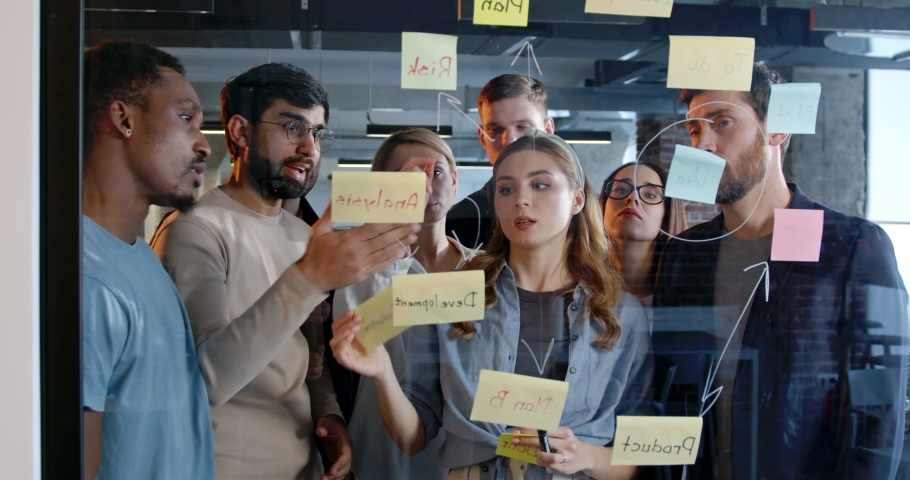 Multiethnic team of startup planning future tasks and to-do list in office. Men and women discussing work and future of company of project. Brainstorming meeting. Working conversation.