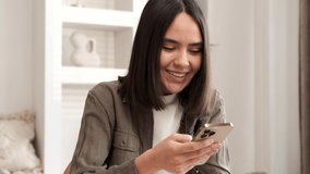 Happy woman smiling looking at camera. Home office interior. Business woman closeup portrait. Girl using smartphone internet surfing communication online. Pretty woman holding phone. Slow motion 