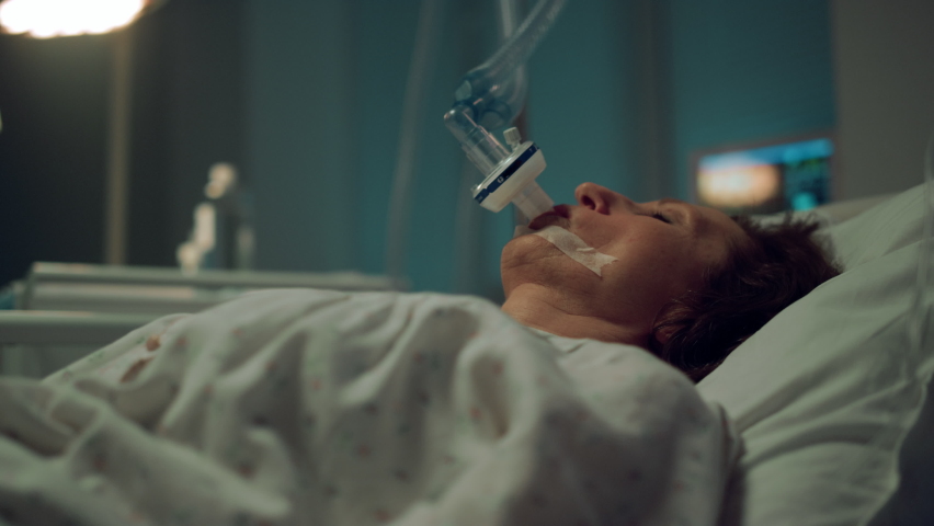 Patient breathing oxygen mask in hospital closeup. Terminally ill person clinic. Unconscious female patient undergoing treatment attached to artificial breathing tube. Sick woman infected with corona. Royalty-Free Stock Footage #1089255693