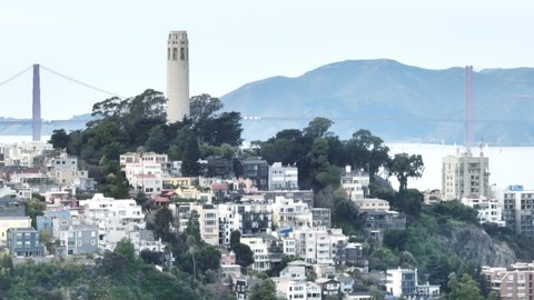 4K Aerial drone of San Francisco cityscape with white tall historic building of Coit Tower on cloudy gloomy day with Golden Gate bridge on motion background. San Francisco city hills b roll, USA