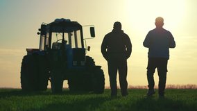 Teamwork concept. Silhouette two male farmers walking in a green field against sunset. Team farmers stand in a field on the background of agricultural machinery. Agronomists discuss harvest. - Powered by Shutterstock - Get 15% off with code: PIKWIZARD15