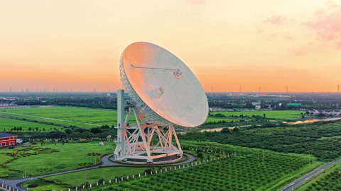 Aerial footage of astronomical radio telescope and beautiful sky clouds at sunset. Radio telescopes are used in science for space observation and distant objects exploring. 
