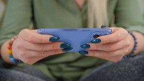 Gamer girl playing mobile game on smartphone. Young female using modern blue mobile gadget to play video games