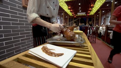 Guangzhou, China -04.26.2017 A restaurant employee cuts a portion of Peking duck and serves a delicacy of roast duck in Beijing, China.