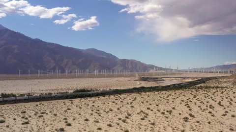 Palm Springs , California , United States - 02 02 2022: Cargo freight train near Palm Springs with windmill farm in distance.