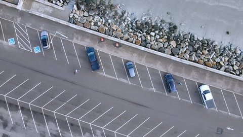 Birds eye view of beach parking at Nantasket beach, Massachusetts. Walkers, runner and young man with a dog pass by.