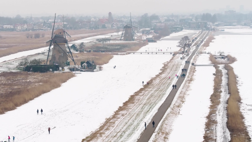 Dutch ice skaters by old Kinderdijk world heritage windmills on cold winter day