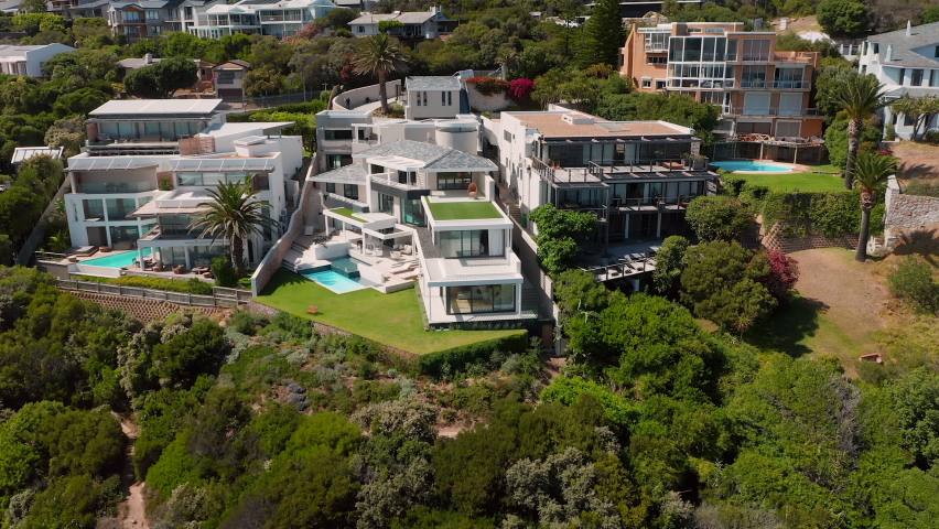 Beautiful Modern Villas With Swimming Pools Surrounded By Lush Greenery In Llandudno Beach, Cape Town, South Africa. - Aerial Rotating Shot