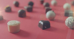 Animation of light over chocolate pralines on red surface. sweets, desserts and chocolate concept digitally generated video.