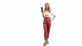 Confident blond-haired beauty, young European girl taking a video for her social media followers or using video phone call to communicate with her friends and family. Copy space, white background