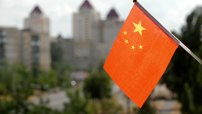Flag of the China set against blue sky and city street. Gold Stars on the red Chinese flag. Chinese flag waving. The holiday flag of the China on the sun. The streets of Beijing. Copy space for text Royalty-Free Stock Footage #1089272219