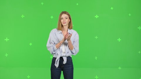 Portrait of sarcastic woman clapping in hands, applauding and looking at camera with smile, bravo, wearing shirt. studio shot isolated on green screen background