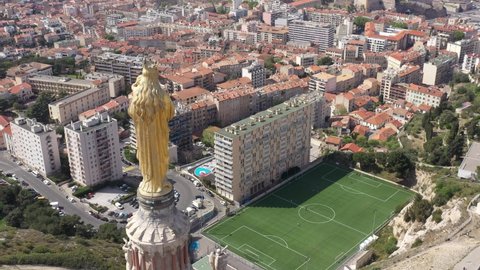 France, Marseille. Francis Di Giovanni footbal Stadium with Notre-Dame de la Garde basilica and its gold statue in the foreground, drone aerial view on a sunny day.