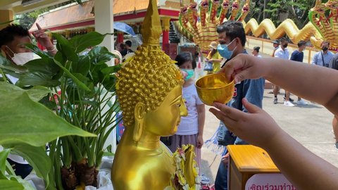 Pattaya, Thailand - April 14, 2022: People bath a Buddha image at the Big Buddha temple during the Songkran holiday. Songkran's water splashing is forbidden this year due to COVID-19 pandemic.
