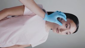 Vertical video of young asian woman doing beauty treatment cosmetic surgery. Cosmetologist hands applying cheek syrine injection on background.