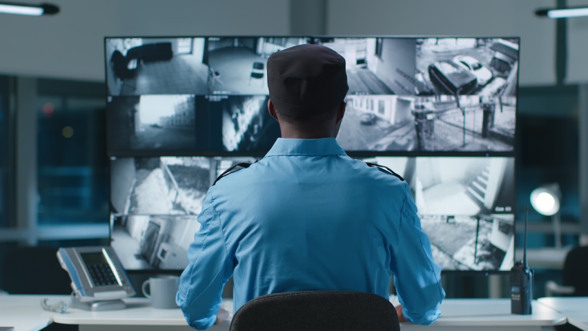Back view of African American security operator use computer with screens showing surveillance camera footage .  Royalty-Free Stock Footage #1089286745