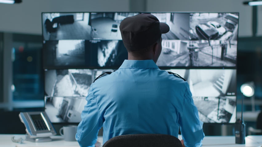 Back view of African American security operator use computer with screens showing surveillance camera footage .  | Shutterstock HD Video #1089286745