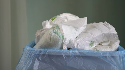 Dirty baby diapers into the trash. Disposing of used nappies. Disposable personal hygiene items