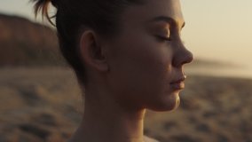 Portrait of tranquil yogi woman meditating on seacoast. Close up sportswoman face with closing eyes illuminated soft sunset light. Attractive yoga girl relaxing on nature making breathing exercises. - Powered by Shutterstock - Get 15% off with code: PIKWIZARD15