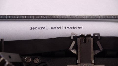 Typing phrase "General mobilization" on retro typewriter.