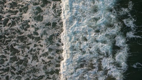 Top down view of stormy sea causing big waves while creating textured sea foam. 4K Drone Video