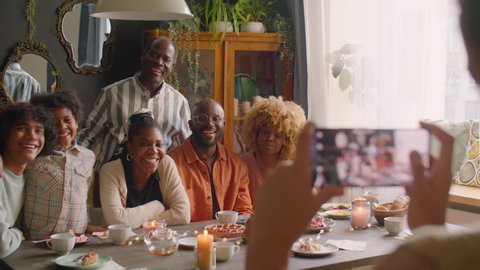 Large African American family smiling and posing together on camera at home holiday dinner while kid taking picture with smartphone Stock Video