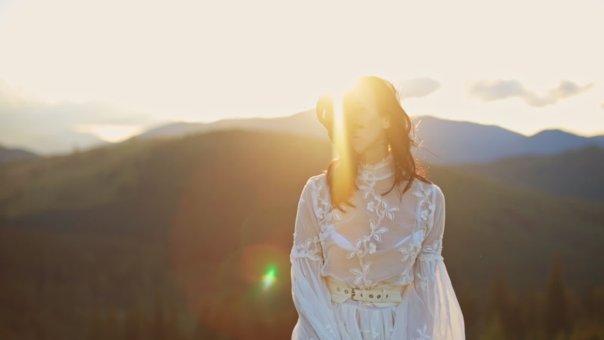 Outdoor happy woman dancing on the nature. Young beautiful lady in dress walking in mountains.