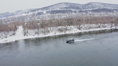 Aerial shots of a hovercraft traveling fast along the river near the shore