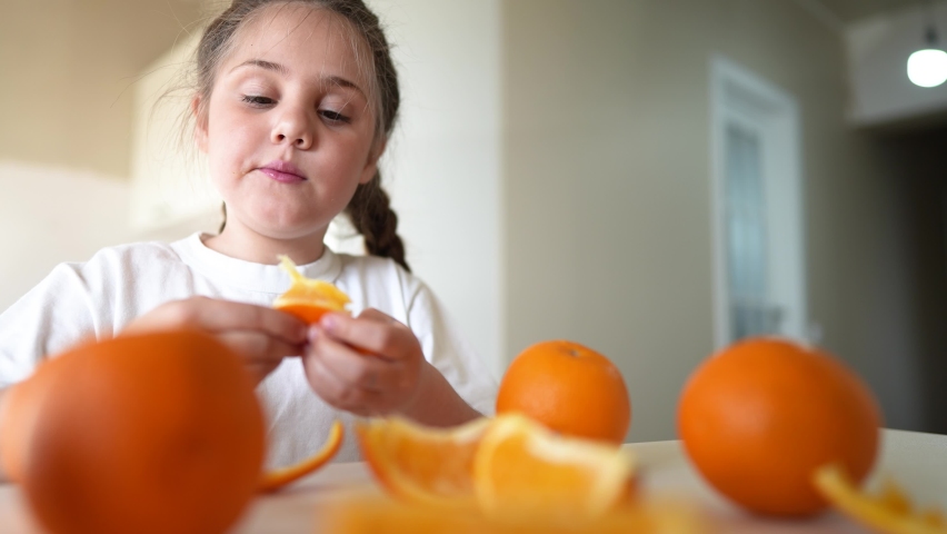 girl child eating oranges. dream happy family fruit healthy food kid concept. little girl daughter eating oranges indoors at the table in the kitchen. juicy fruits oranges are for a healthy diet Royalty-Free Stock Footage #1089301865
