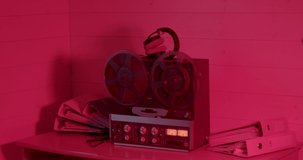Red light of the night room. Tape reels spin on an old tape recorder. Headphones are on the device. There are documents on the table, the work of the criminal service.