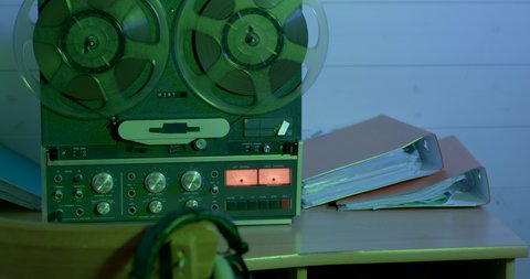 Rotation of film equipment on an old-style tape recorder. There are folders on the table. A place where evidence of the subject's conversations was recorded.