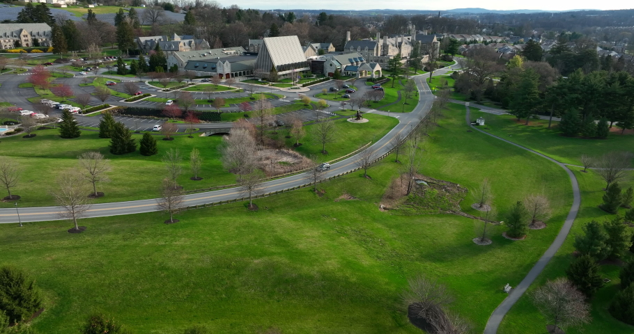 Car drives on road through large estate, retirement community in USA. Aerial in spring.