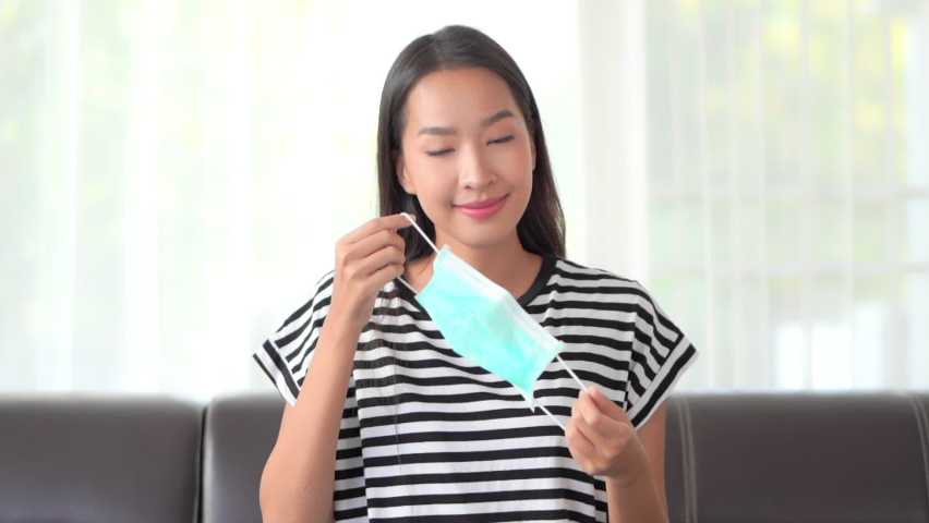 A very attractive young woman demonstrates putting her surgical mask on.