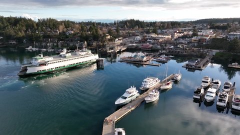 Cinematic 4K aerial drone footage of the Washington State Ferry arriving in Port and town of Friday Harbor with the ferry terminal, commercial zone, downriggers in the San Juan Islands