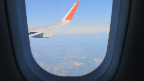 wing of aircraft in the window. wing of the plane flies over the clouds in the sky, the view from the window to the cloudy sky against the background of earth. Departure abroad. I love to travel
