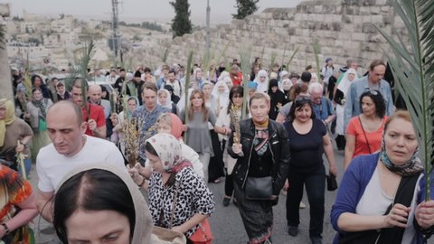 Jerusalem, Israel Apr 10, 2022: Believers crowds with fresh branches walk along old city street on Palm Sunday. Entrance into Jerusalem christian holiday celebration