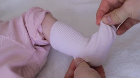 Caring father dressing baby girl. Close up hands putting on sock and tickle on foot.