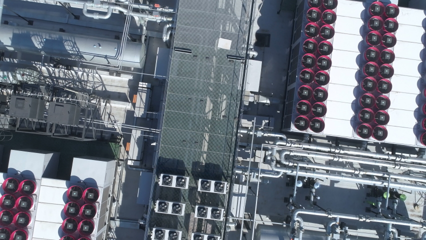 Overhead look down. Datacenter roof with rooftop fans, piping and tanks of HVAC aircon cooling system. Royalty-Free Stock Footage #1089313053