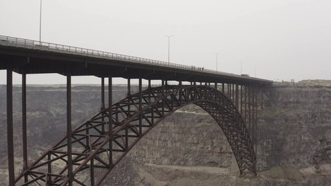 Aerial View of Base Jumpers on Perrine Bridge, Twin Falls, Idaho USA. Jumping From Top In Canyon of Snake River, Drone Shot Tracking Closer Towards Bridge and Jumpers, Overcast