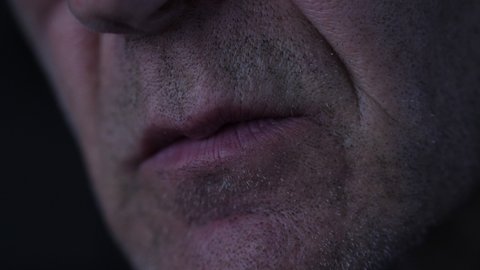 Close up of hacker's mouth talking frantically while looking at computer screen in the dark. 
