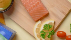 Vertical flat lay: the chef smears a piece of salmon with sauce before baking on the colorful background