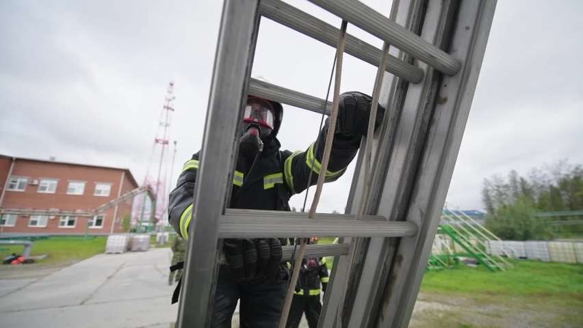 Firefighter in gas mask and protective suit climbs the stairs during an exercise
