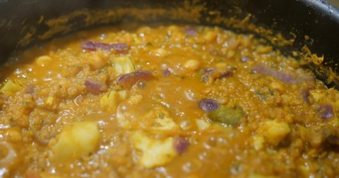Indian cooking : Red Lentil Dhal. Close up of vibrant red lentils simmering. Professional asian exotic recipe
