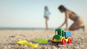Many bright multi-colored plastic toys lie on a large sea sandy beach near the blue stormy mysterious sea under the warm summer sun